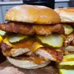 Hot honey chicken sandwich with melted cheddar cheese and pickles on a toasted bun
