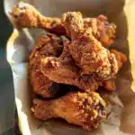 Crispy Cajun fried chicken drumsticks in a takeout tray with golden brown coating