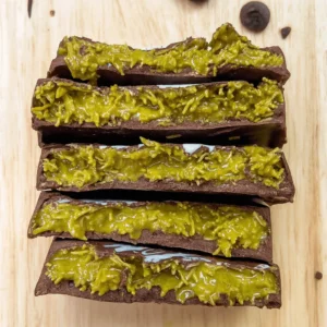 Homemade pistachio chocolate bars sliced on a wooden board